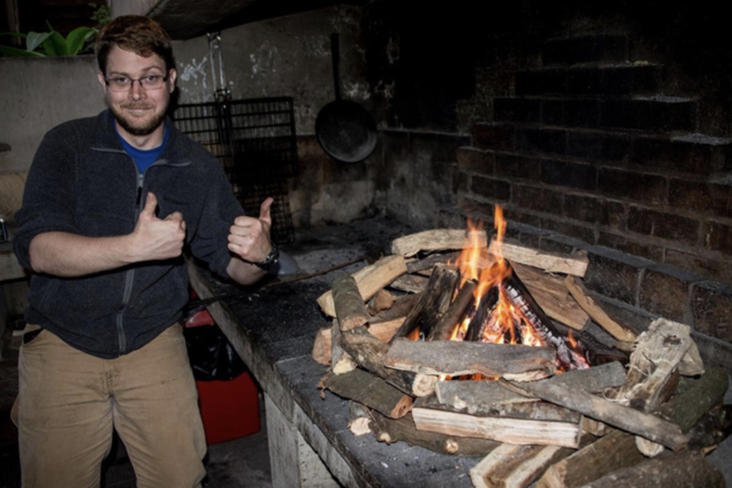 student giving a thumbs up by a fire