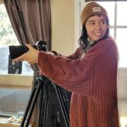 Madjelyn smiling while recording with a film camera