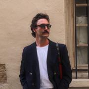 Grant standing in front of wall with sunglasses