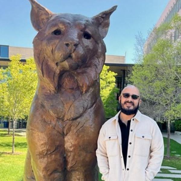 Manuel Sisneros standing next to Mio statue