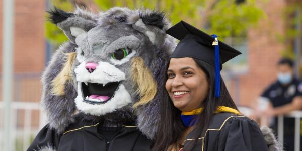 Mascot Milo with MA student in robes.