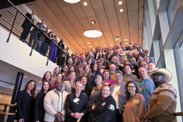 A large group of C-CHEP conference attendees, including CU Denver faculty, students, and community partners, posing together on a grand staircase at the January 30, 2026 conference
