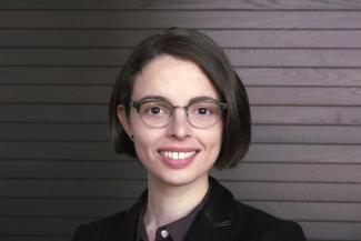 A white woman with short brown hair and glasses.