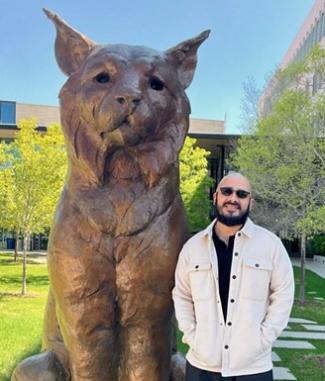 Manuel Sisneros standing next to Mio statue
