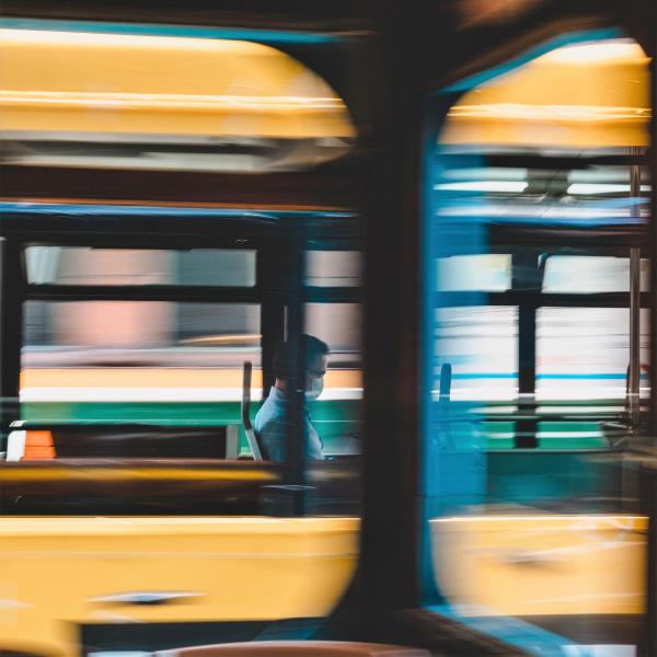 Man riding on a bus with a face mask on.