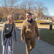 Kurt, a CU Succeed teacher, and Kathleen, a student, walk on campus laughing.