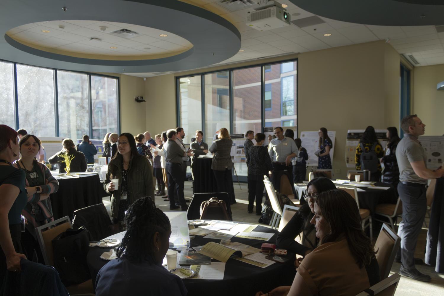 Photo of large group of faculty, staff, and students looking at research posters and displays.