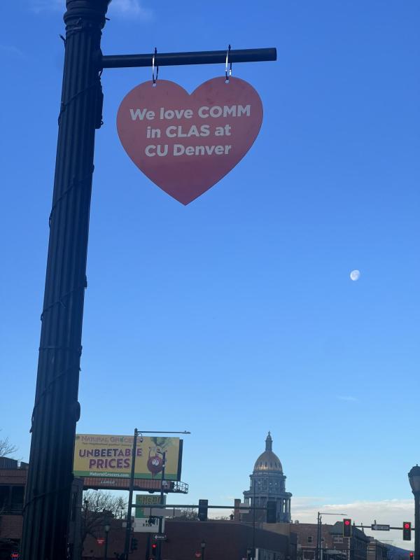 Heart shape hoisted on a lamppost saying We Love COMM in CLAS at CU Denver