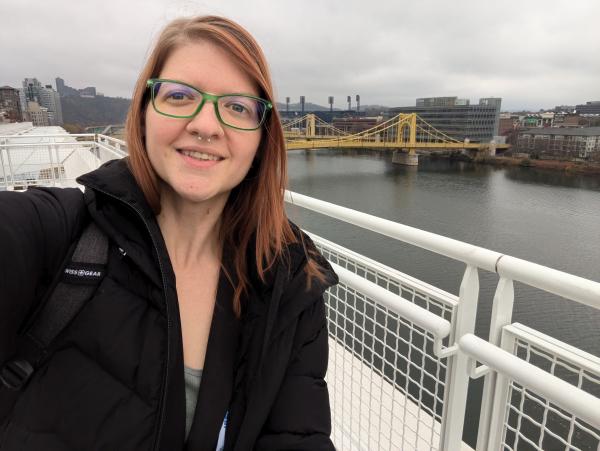 Jami Helmig, CLAS' Fall 2024 Outstanding BS Student, stands against city background