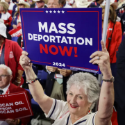 woman holds sign that reads Mass Deportation Now