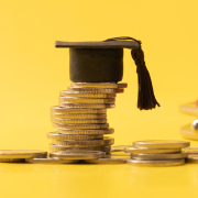 A graduation cap on top of quarters to imply the awarded grant money 