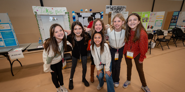 group of students posing in front of science fair posters