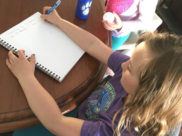 girls writes in notepad at table