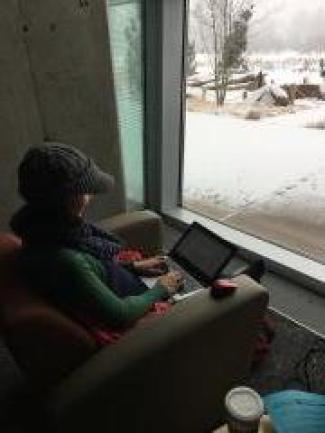 Woman sitting in a chair writing at a laptop