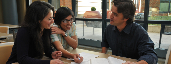 Economics professor working with students around a table