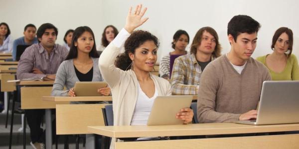 Students in classroom, woman raising her hand