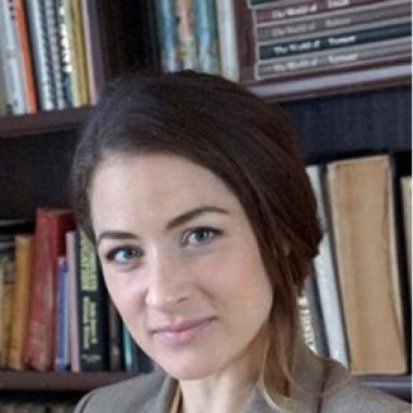 Brown-haired woman with her hair back wearing pale yellow shirt under a light grey blazer