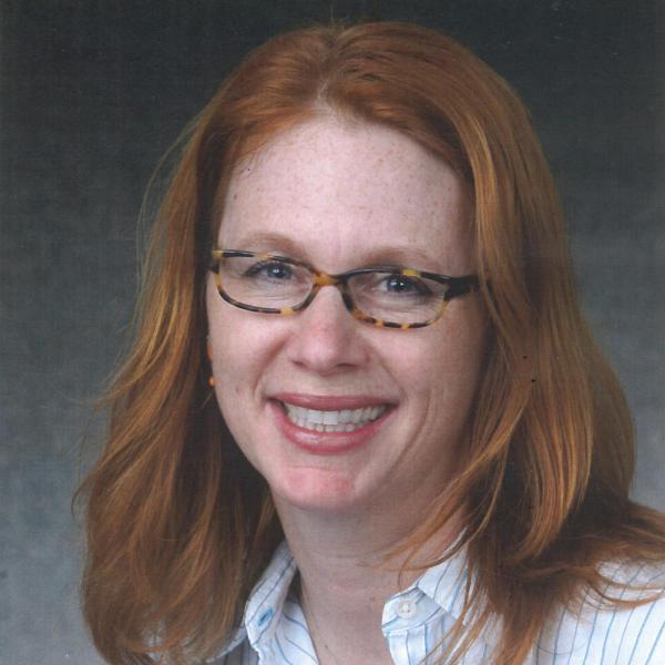 Headshot of red-haired woman wearing glasses