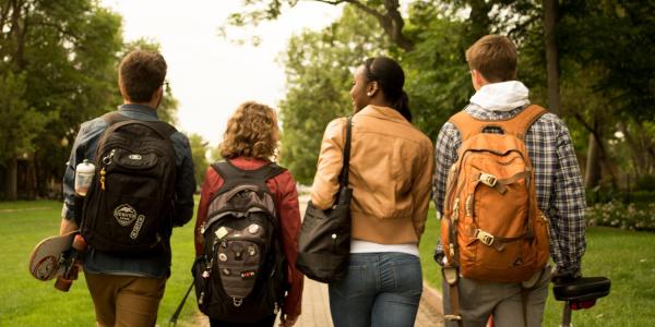 Four students walking down a sidewalk