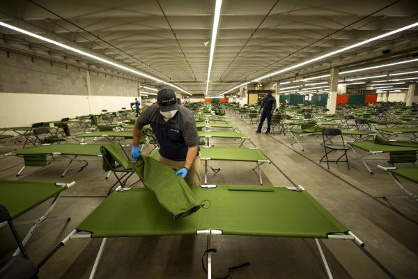 The inside of a homeless shelter in Denver. Hundreds of cots are laid out in a large room. 