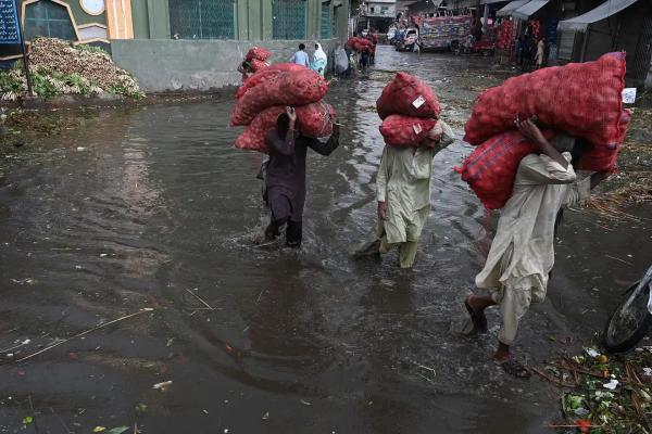 Workers carry sacks of potatoes at a flooded market in Lahore.