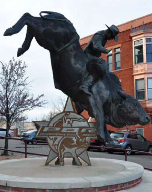 A statue depicting a cowboy skillfully riding a bull, showcasing the spirit of rodeo culture.