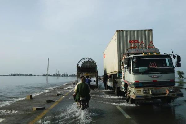 Vehicles move along a flooded road after rains in Mehar, Sindh province.