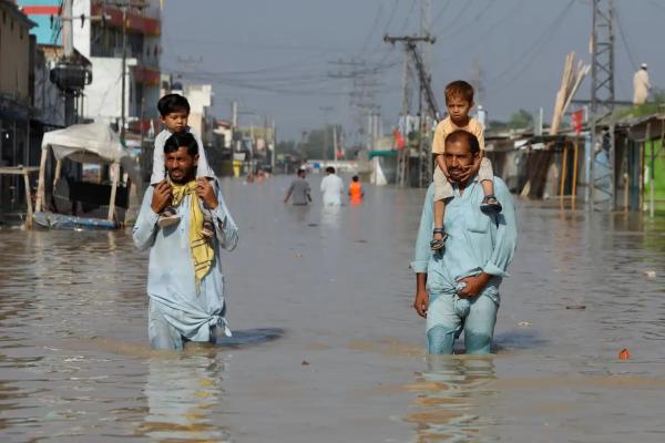 Men carry children on their shoulders in Nowshera.