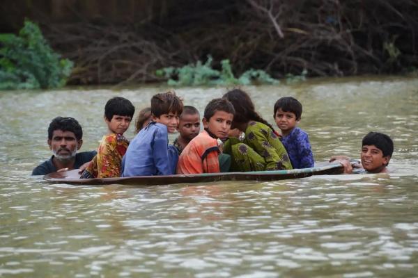 A man uses a satellite dish to move children across a flooded area in Jaffarabad district, Balochistan.