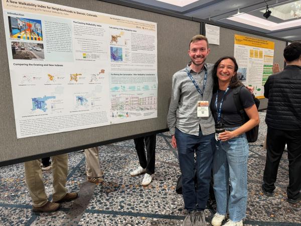 Dan Schumacher and Rachel Thody smile beside a research poster titled “A New Walkability Index for Neighborhoods in Denver, CO” at a conference poster session.