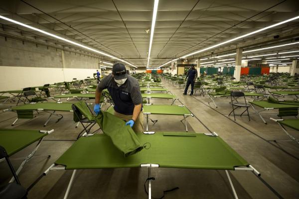 The inside of a homeless shelter in Denver is shown. Hundreds of cots are laid out in a large room. 