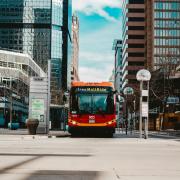 An RTD free MallRide bus stopped on Denver's 16th Street Mall between downtown skyscrapers, with the Tremont stop sign and state capitol dome visible in the background. Photo by Eric Francis on Unsplash.