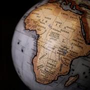 Close-up of a globe focused on the African continent against a dark background, showing country names including Nigeria, Sudan, Ethiopia, Kenya, Tanzania, and South Africa. Photo by James Wiseman on Unsplash.
