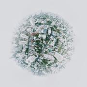 Aerial "tiny planet" view of a cityscape with tall buildings and greenery, forming a spherical shape against a light sky, conveying urban density. Photo by Joshua Rawson-Harris on Unsplash.