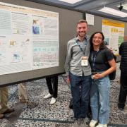 Dan Schumacher and Rachel Thody smile beside a research poster titled “A New Walkability Index for Neighborhoods in Denver, CO” at a conference poster session.
