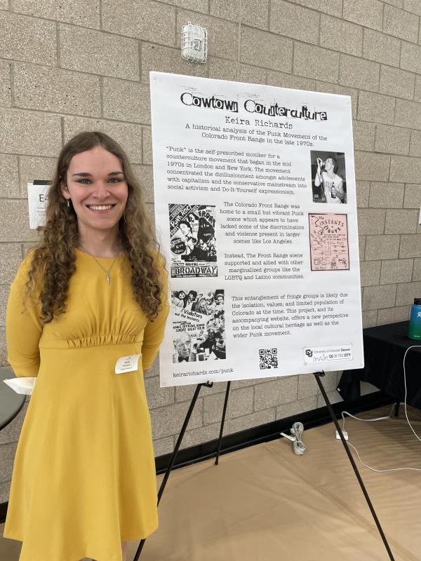 Graduating senior, Keira Richards, stands in front of a poster presentation of her project "Cowtown Counterculture."