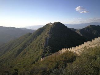 Picture of the Great Wall of China surrounded by green trees.