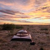 Goran's tent in a grassy area with a sunset in the background