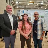 CU Denver Chancellor stops for a photo with researchers Sachiel Oberto and Ali Alghamdi and their RACAS poster. 
