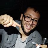 Master's student Goran Shikak with a small scorpion dangling from his finger.