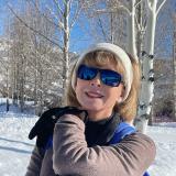 Dr. Diana Tomback smiles as she hikes up a snowy hill. 