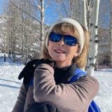 Diana Tomback leaning on her ski poles near a grove of white pine