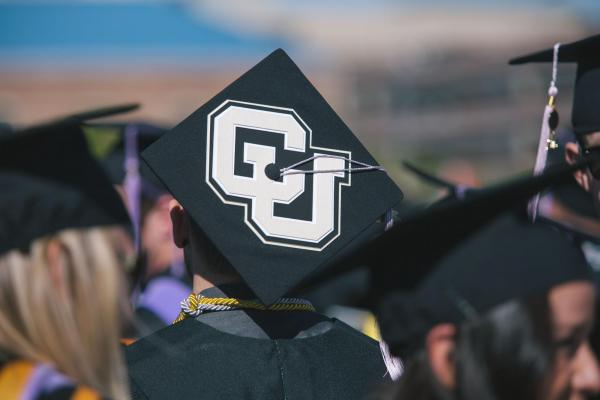 a person wearing a graduation cap with the CU logo on it
