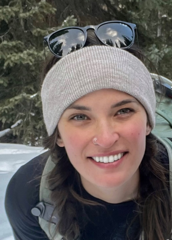 Alyssa outdoors wearing a knit hat smiling at the camera
