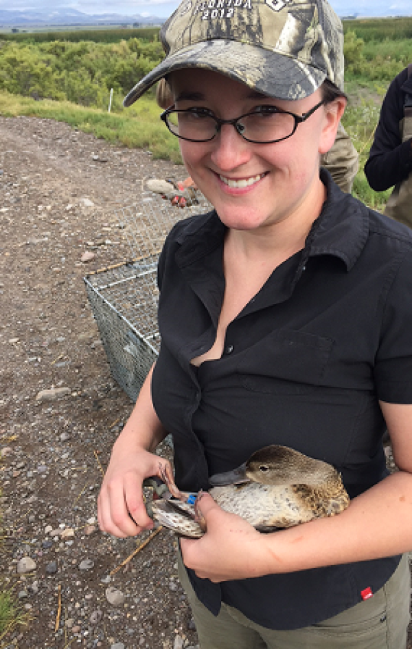 Dr Buderman is holding a duck while smiling for the camera