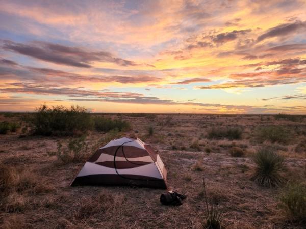 Goran's tent in a grassy area with a sunset in the background