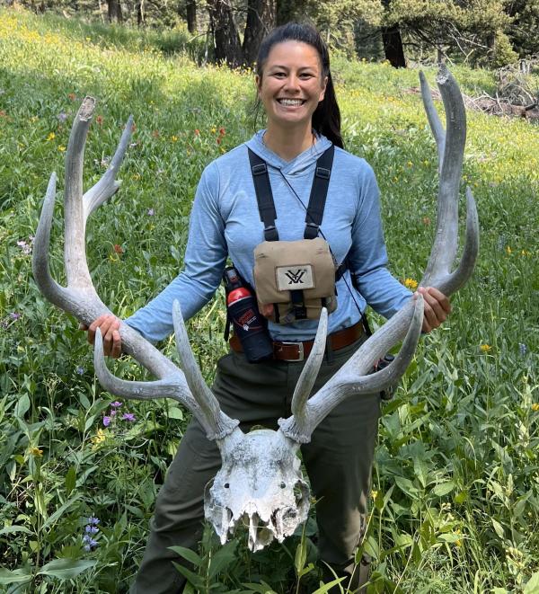 Karina Li holding an elk skull with large antlers.