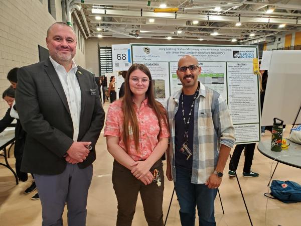 CU Denver Chancellor stops for a photo with researchers Sachiel Oberto and Ali Alghamdi and their RACAS poster. 