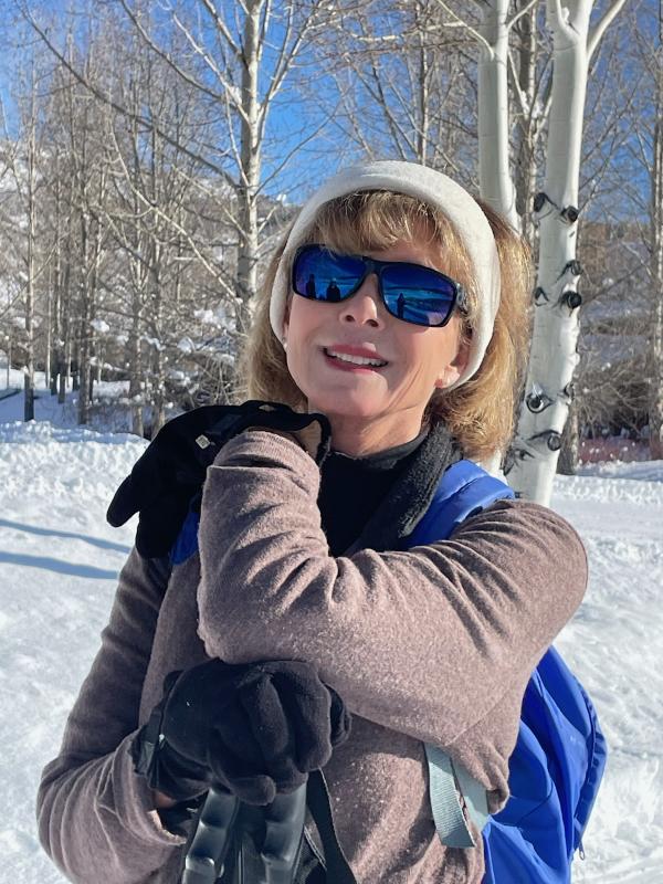 Diana Tomback leaning on her ski poles in the snow mountains