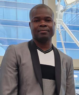 Jerome wearing a gray blazer standing in front of a building